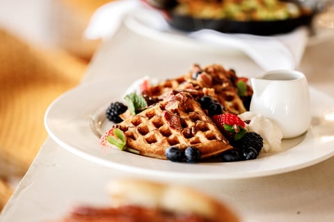 Golden waffle topped with fresh berries and whipped cream