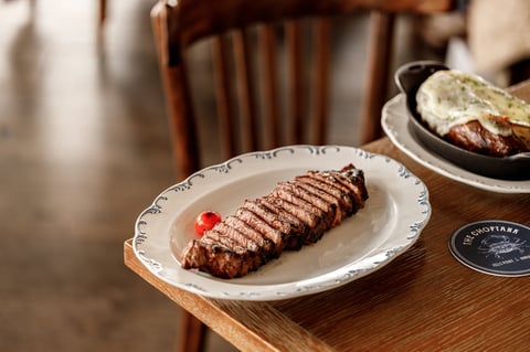 Grilled steak with grill marks on a decorative white plate